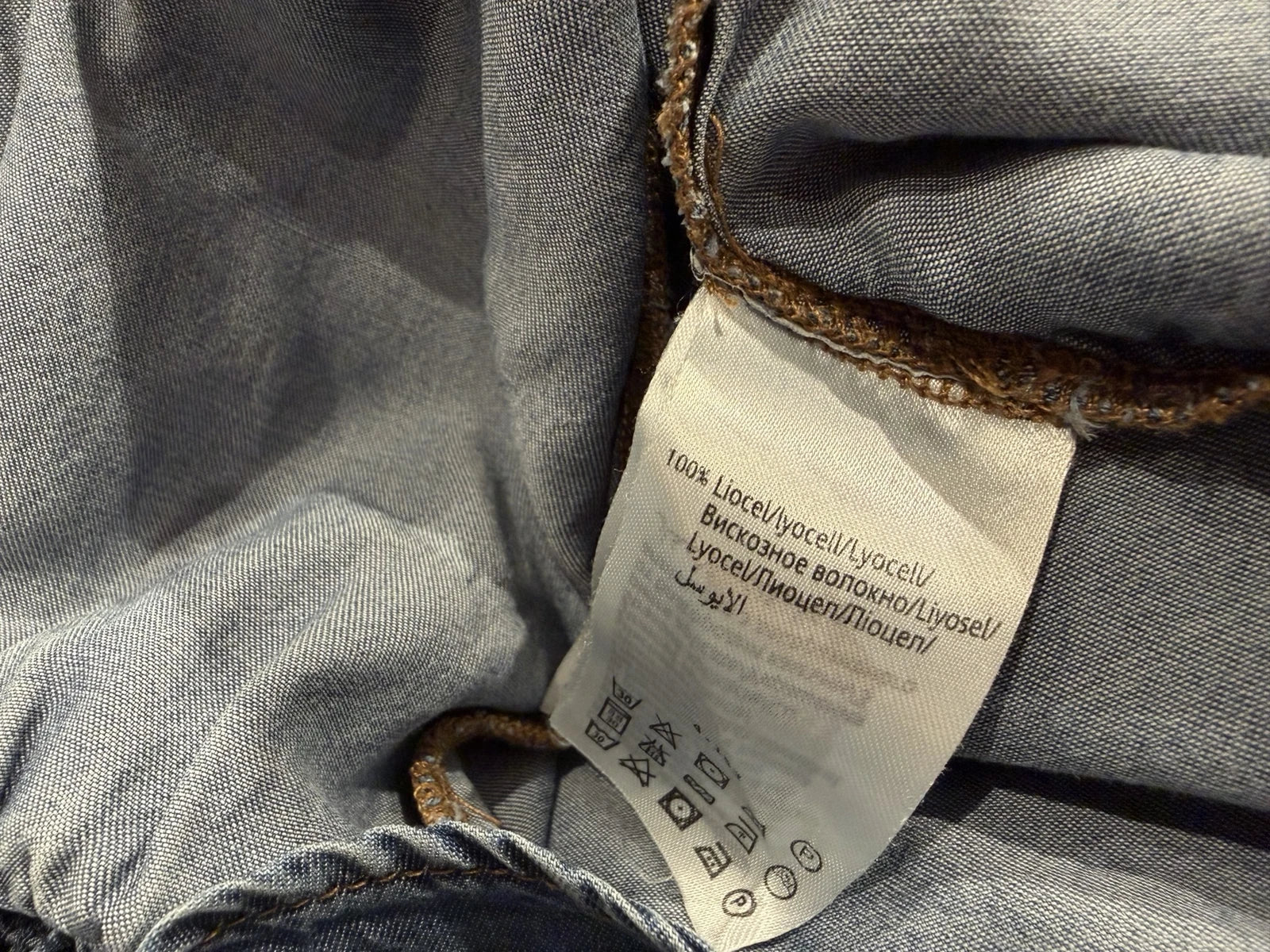 Clothing care label showing 100% lyocell, illustrating how to read fabric composition labels and identify natural, regenerated and plastic-based fibres.