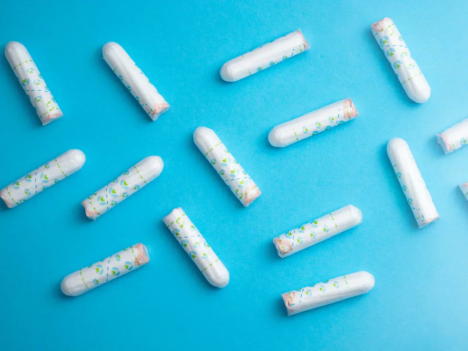 Disposable tampons on a blue background illustrating plastic, PFAS and chemical transparency in period products.