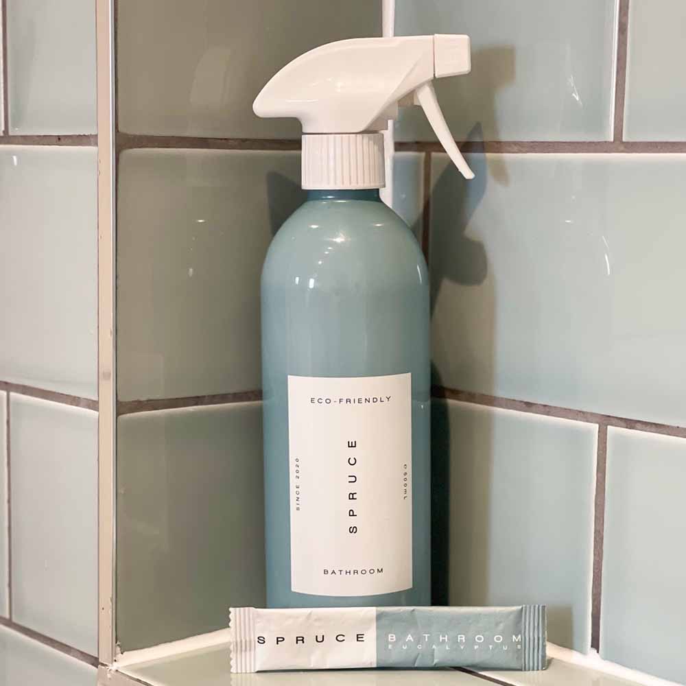 A tile cleaner spray and refill in front of tiled wall in bathroom