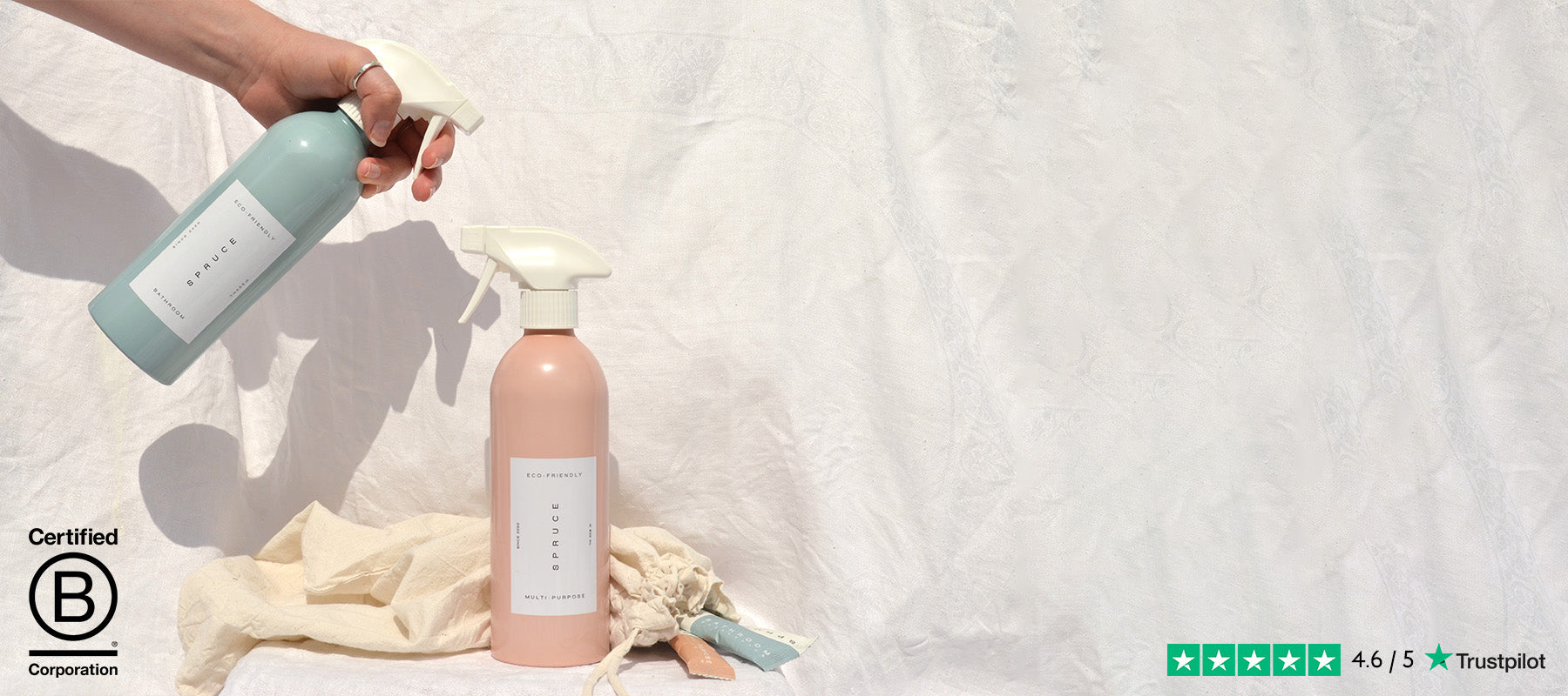 Hand holding eco friendly cleaning products in front of a white sheet