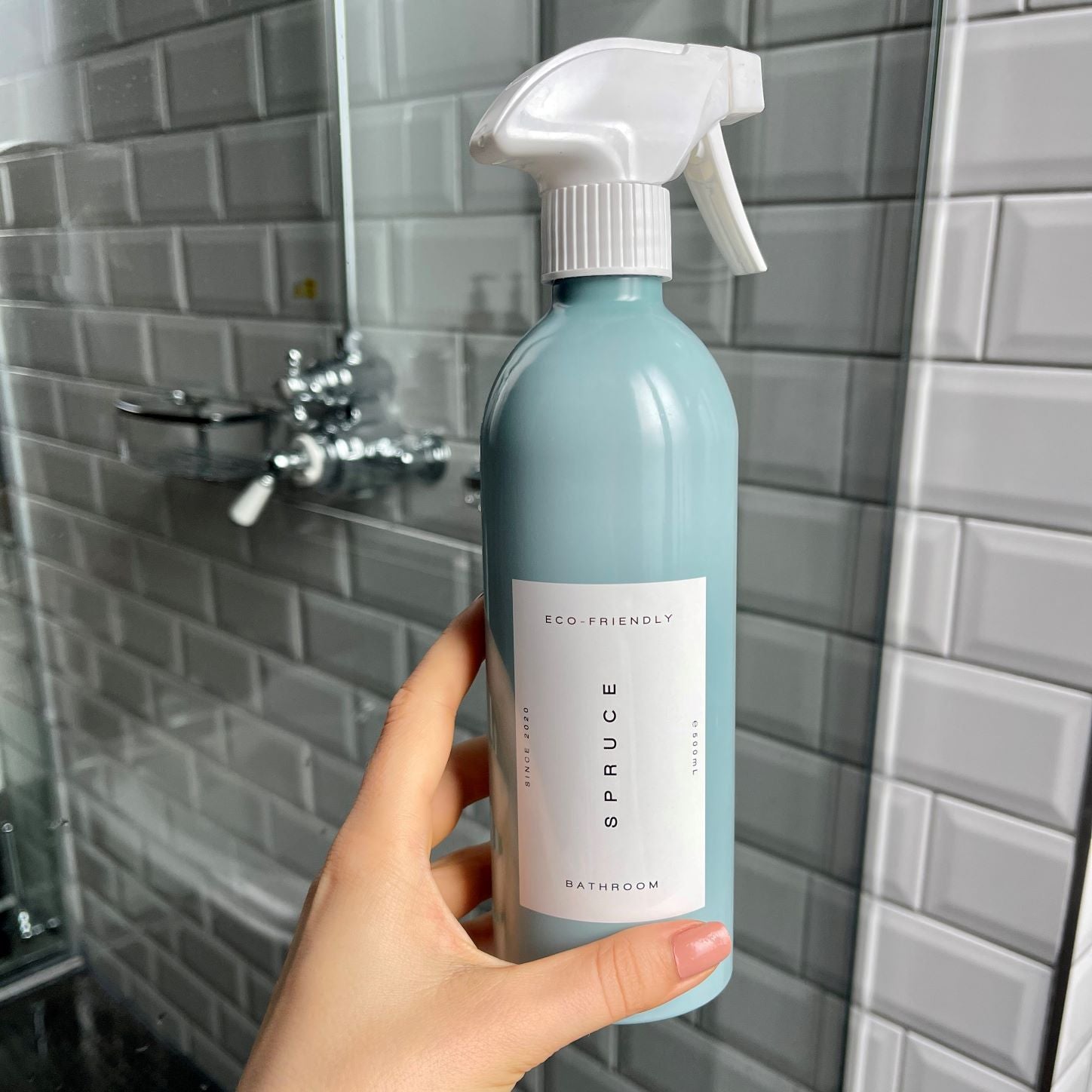Hand holding tile cleaner in front of shower